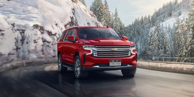 The 2024 Radiant Red Tintcoat Chevy Suburban Cruising Through an Icey Mountain Road