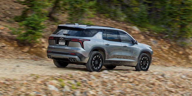 Side Profile View of the 2024 Chevy Traverse Driving on a Gravel Path