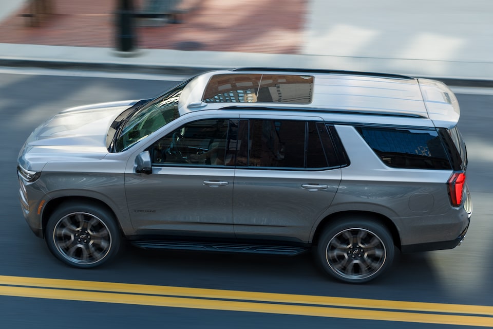 Birds-Eye Side View of the 2025 Chevrolet Tahoe SUV Driving on a Road